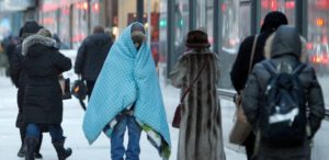 A homeless man bundles up in blankets on a January morning in downtown Chicago. Officials say seasonal changes may account for discrepencies between perceptions of how many homeless people live in Chicago, and the decline documented by this year's point-in-time count. (Kiichiro Sato/AP Photo)