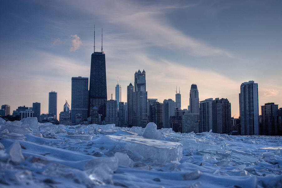 The skyline of Chicago is visible behind a foreground of ice and snow.