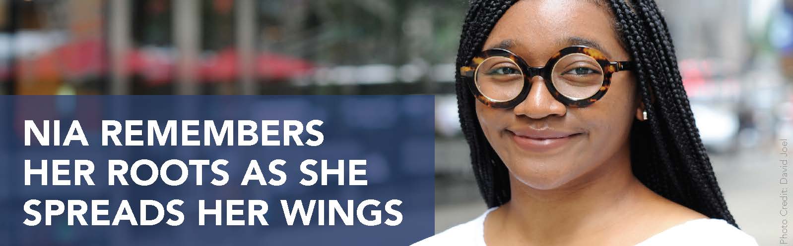 Close-up smiling portrait of Nia Hill, a Black woman in her 20s. She is wearing a white top and large, round, tortoise-shell glasses. Banner text reads: Nia remembers her roots as she spreads her wings.